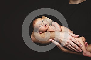 Newborn baby in his father`s hands in dark