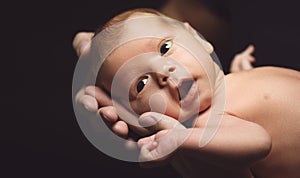 Newborn baby in his father`s hands in dark