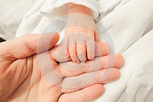 Newborn baby holding father finger