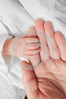 Newborn baby holding father finger