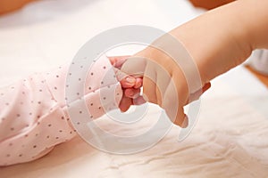 . Newborn baby holding finger of older child.