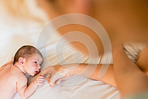 Newborn baby holding his mother`s hands tenderly