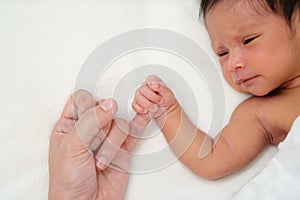Newborn baby holding little finger of mother`s hand
