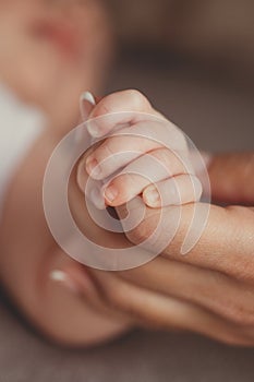 Newborn baby holding mother's finger