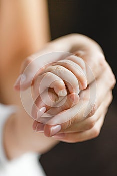 Newborn baby holding mother's finger