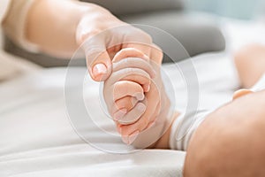 Newborn baby holding mother`s hand with his tiny fingers, closeup