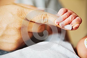 Newborn baby holding parents finger