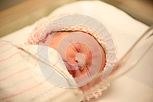 Newborn baby in hospital asleep in blanket