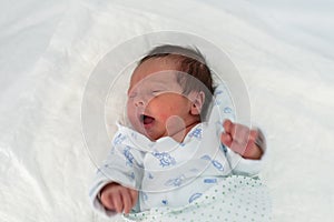 Newborn baby in a hospital crib with a baby blanket