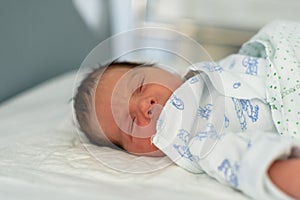 Newborn baby in a hospital crib with a baby blanket