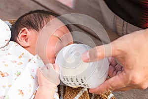 Newborn baby infant eating milk from bottle.