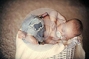 Newborn baby in jeans sleep in basket on floor