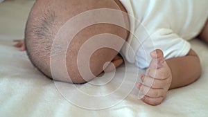 Newborn baby kid who toss and turn, sleeping on his tummy on bed at home. Asian child bottom up sleeping position