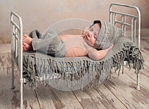 Newborn baby in knitted hat and pants sleeping