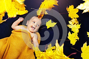 Newborn baby lay in orange autumn maple leaves