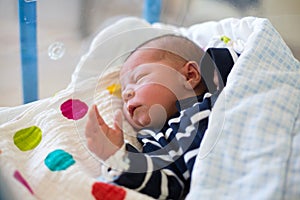 Newborn baby laying in crib in prenatal hospital