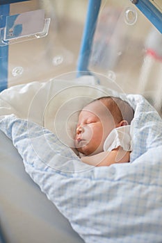 Newborn baby laying in crib in prenatal hospital