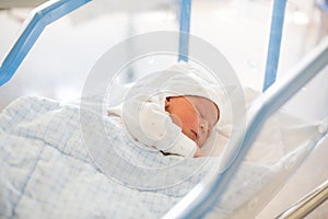 Newborn baby laying in crib in prenatal hospital