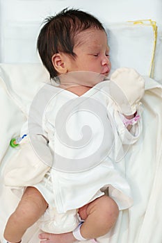 Newborn baby laying and sleeping in infant bassinet basket at hospital