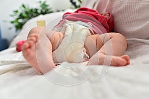 Newborn baby laying on a sofa with disposable diapers ready to change