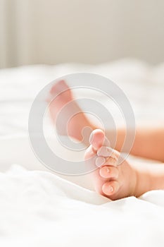 Newborn baby legs in diaper, lying on white bed, top view