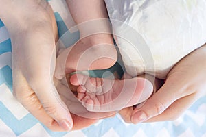 Newborn baby legs in mother`s hands folded by heart, the concept of motherhood
