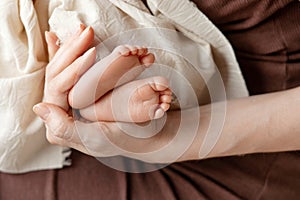 Newborn baby legs  in motherâ€™s palm. Happy mom holding her baby feet close up.Mom and her child. Maternity, family, birth