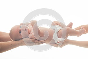 Newborn baby lies awake in diaper on parent hands.