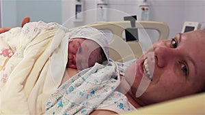 A newborn baby lies on the breast of a happy mother in the hospital. The first minutes of life.