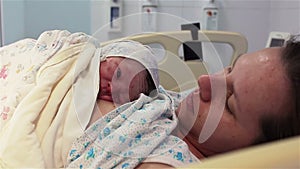 A newborn baby lies on the breast of a happy mother in the hospital. The first minutes of life.