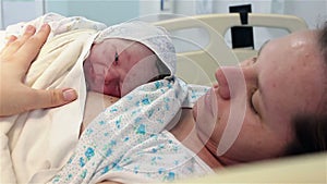 A newborn baby lies on the breast of a happy mother in the hospital. The first minutes of life.