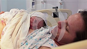 A newborn baby lies on the breast of a happy mother in the hospital. The first minutes of life.