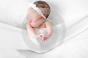 Newborn baby lying on back among white sheets