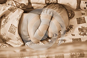 A newborn baby with a maternity hospital bracelet on his arm is sleeping in a crib. A newly born child in a clinic bed behind a