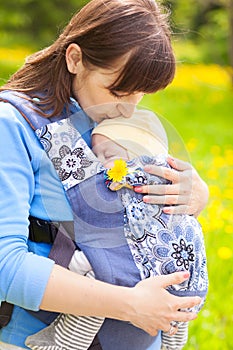 Newborn baby and mother outdoors walking with sling.