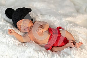 Newborn baby in mouse costume crying on fur bed