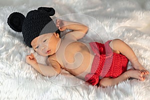 Newborn baby in mouse costume on fur bed