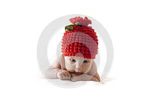 Newborn baby in a red berry cap