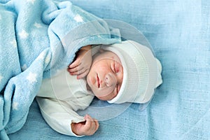 Newborn Baby Red Cute Face Portrait Early Days Sleeping In Medical Glass Bed On Blue Background. Child At Start Minutes