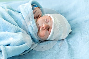 Newborn Baby Red Cute Face Portrait Early Days Sleeping In Medical Glass Bed On Blue Background. Child At Start Minutes