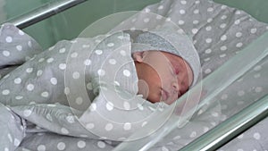 Newborn Baby Red Cute Face Portrait Early Days Sleeping In Medical Glass Bed On Grey Background. Child At Start Minutes
