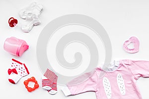 Newborn baby`s background. Clothes for small girl with booties on white top view copy space