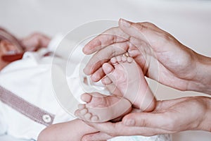 Newborn Baby`s feet on female hands closeup