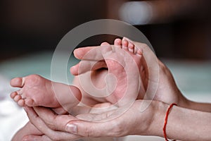 Newborn Baby`s feet on female hands closeup