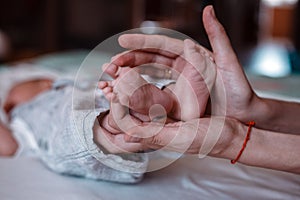 Newborn Baby`s feet on female hands closeup