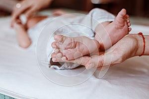 Newborn Baby`s feet on female hands closeup