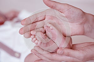 Newborn Baby`s feet on female hands closeup