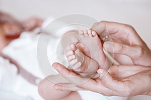 Newborn Baby`s feet on female hands closeup