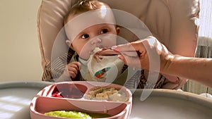 Newborn baby's first complementary feeding, starting baby food with a spoon