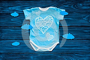 Newborn baby`s sleep concept. To put the child to bed. Baby bodysuit near clouds on blue wooden background top view